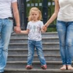 child holding hands of 2 adults, concept of Creating an Effective Co-Parenting Plan That Works