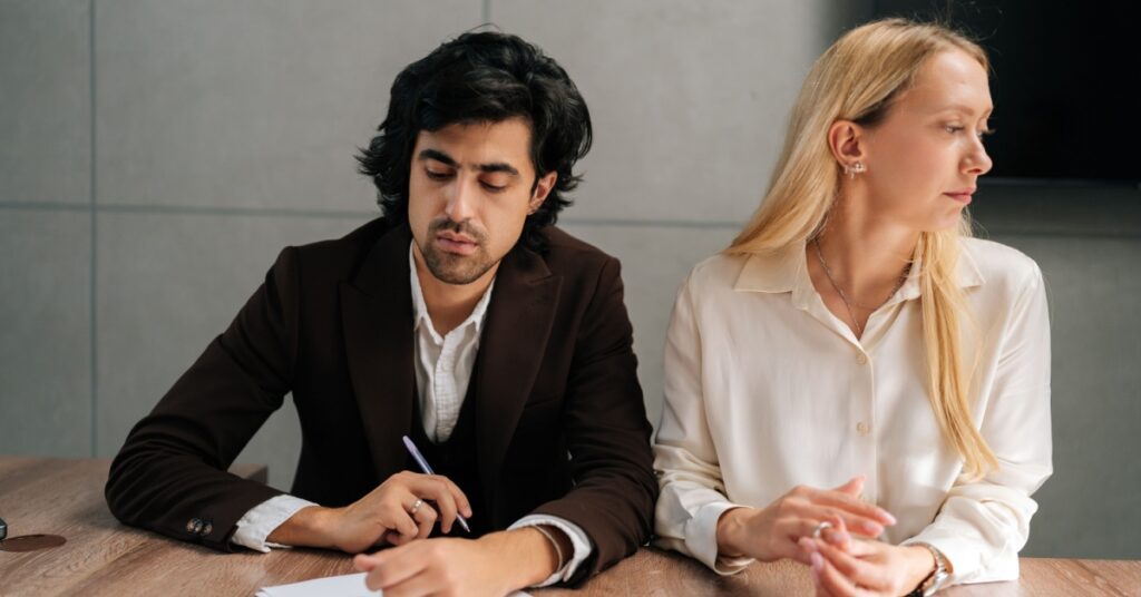 man contemplating signing paper while woman looks away, concept of Who Should File for Divorce First in NJ?