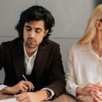 man contemplating signing paper while woman looks away, concept of Who Should File for Divorce First in NJ?