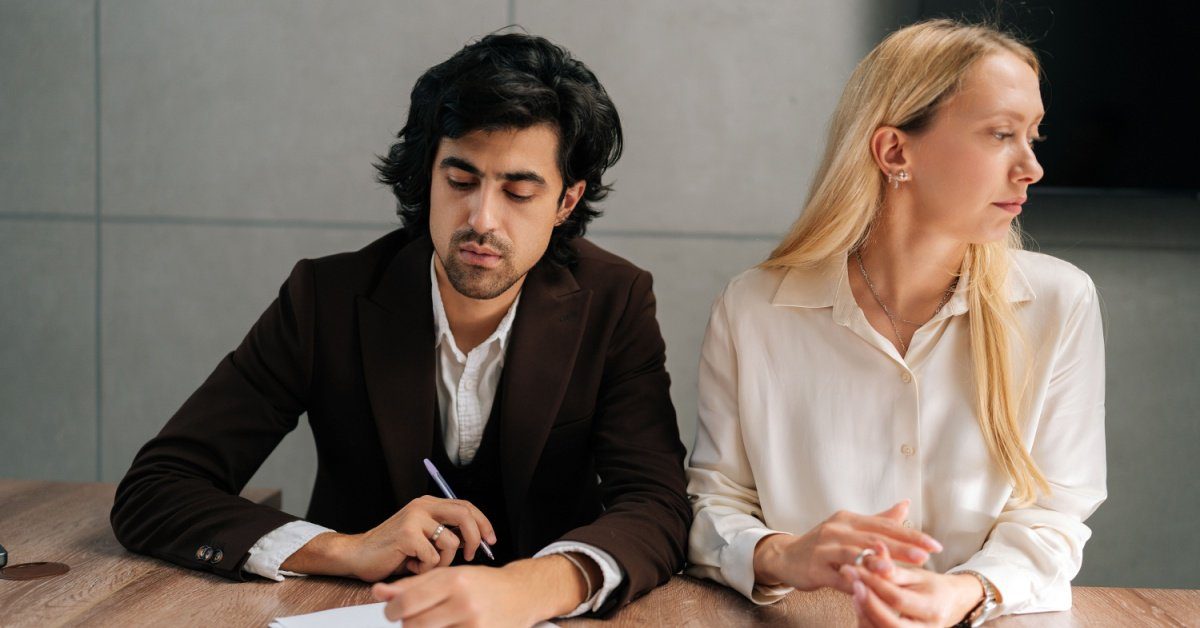 man contemplating signing paper while woman looks away, concept of Who Should File for Divorce First in NJ?