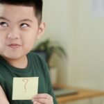 asian boy with bandaid on arm and post it with a question mark, concept of vaccinations
