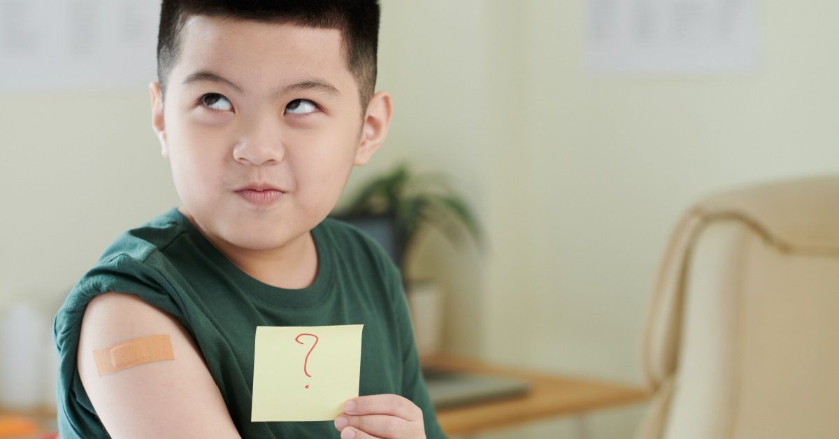 asian boy with bandaid on arm and post it with a question mark, concept of vaccinations